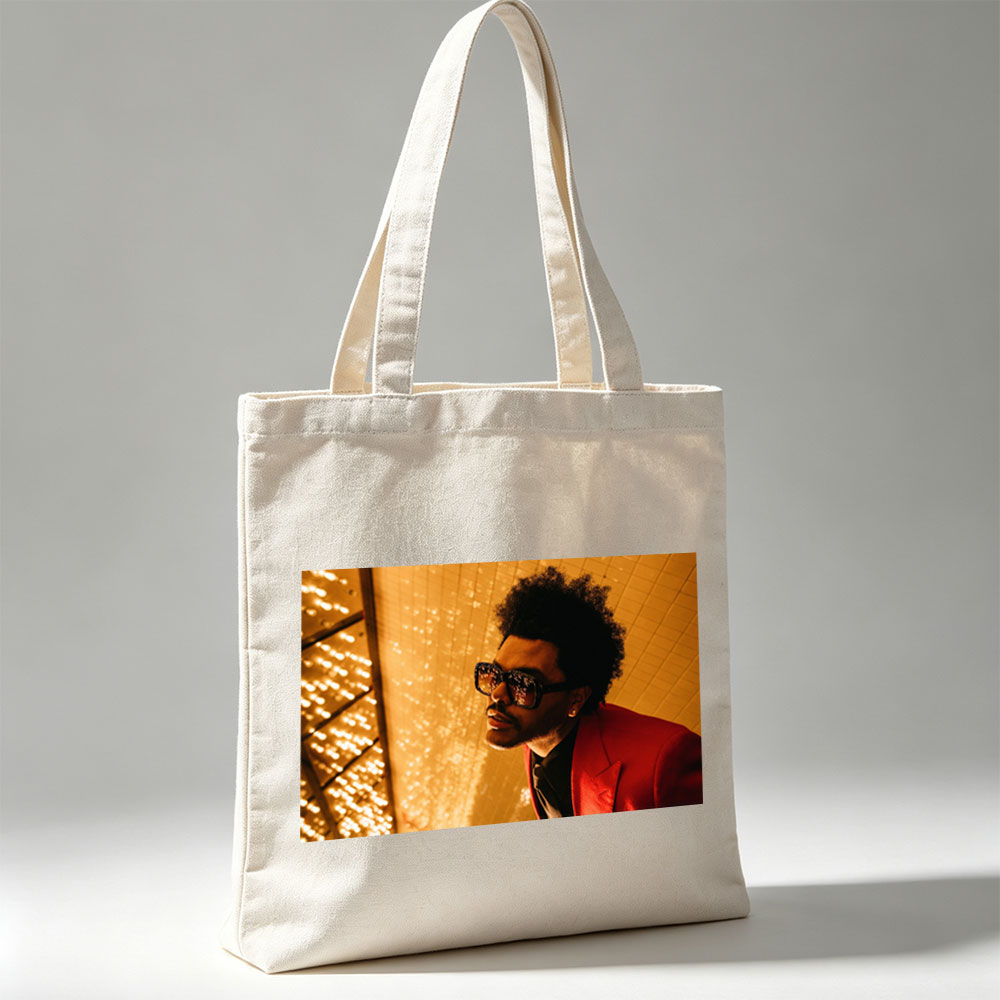 The Weeknd in a Red Suit and Sunglasses Against a Golden Lighted Background - Canvas tote bags