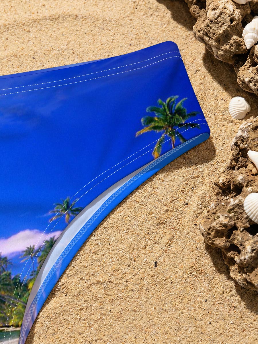 Seagulls soar over a pristine tropical beach with crystal-clear waters and palm trees under a vibrant blue sky. -  Men's swim trunks