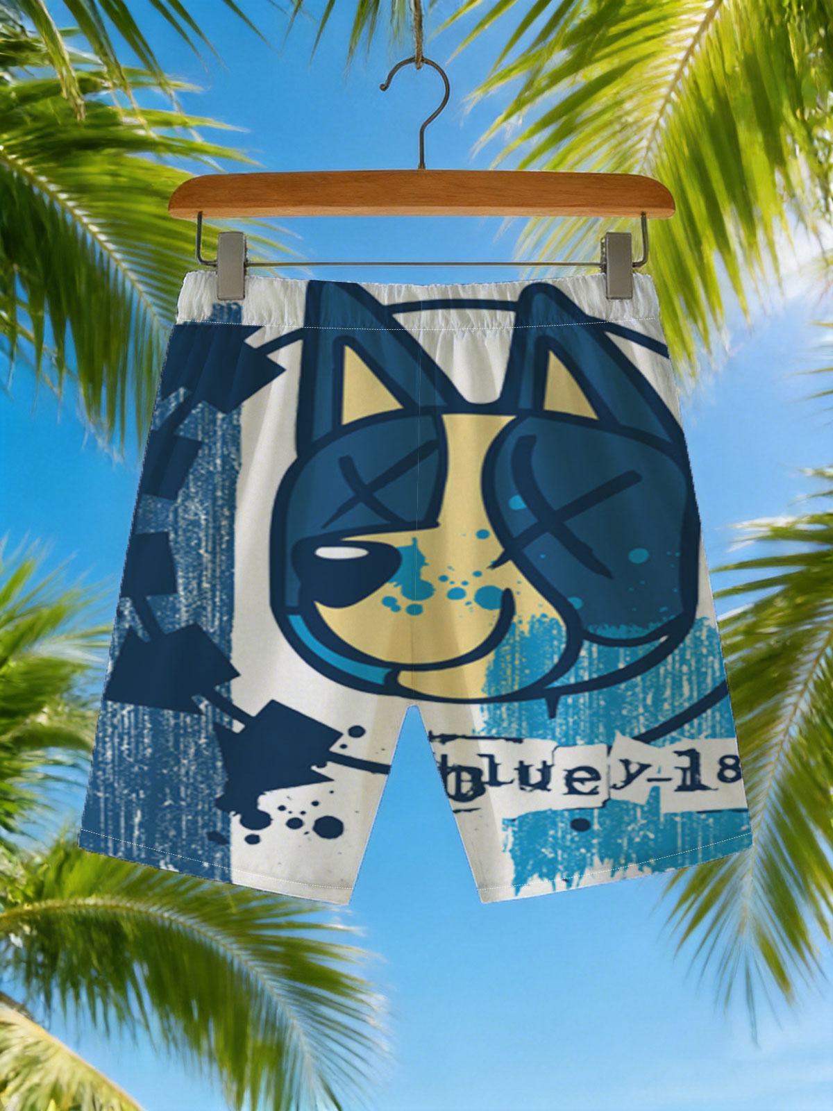 Bluey-182: A stylized blue and yellow cat face with X eyes, arrows, and splatter effects on a textured blue background. -  Beach shorts