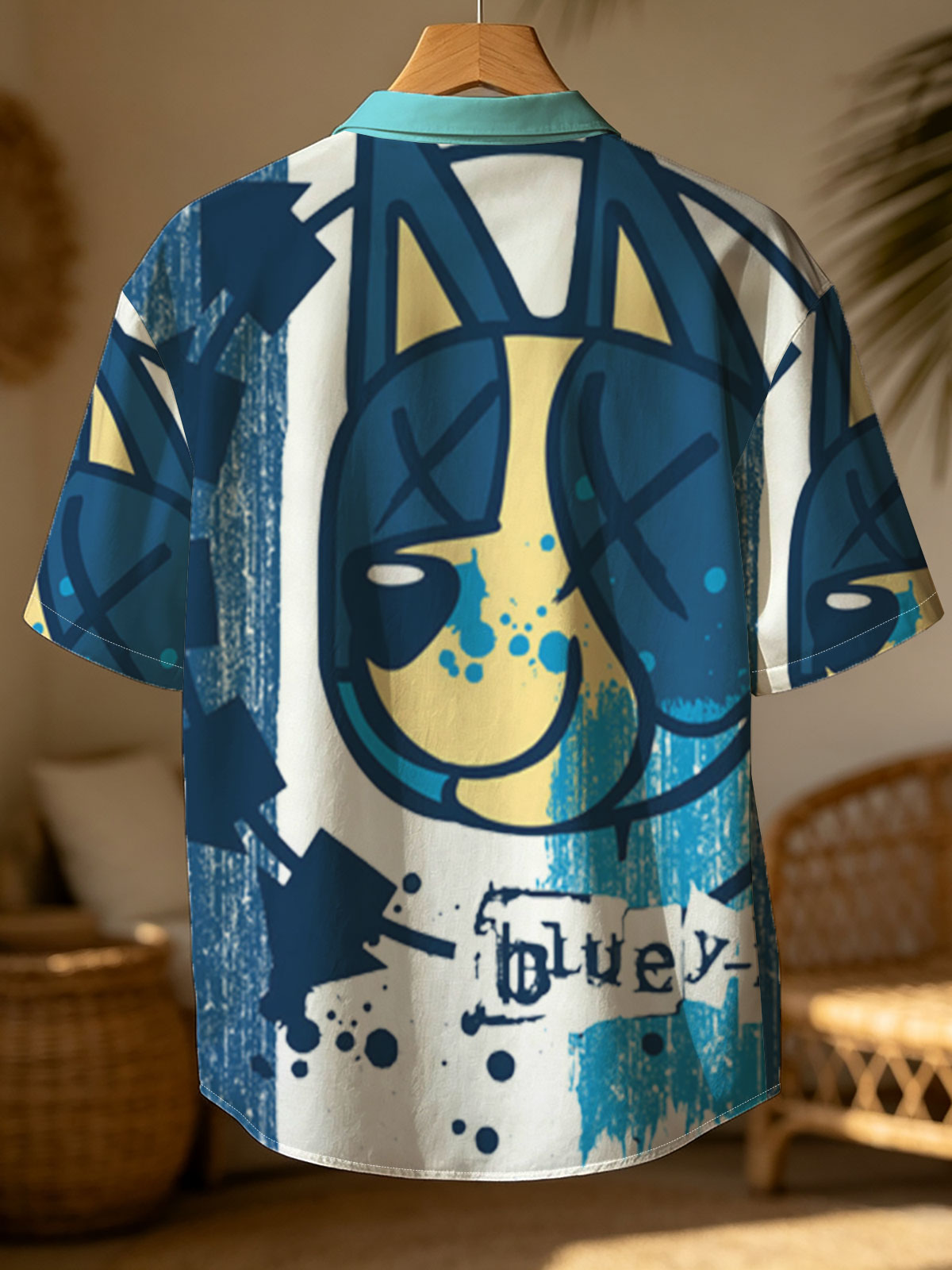 Bluey-182: A stylized blue and yellow cat face with X eyes, arrows, and splatter effects on a textured blue background. -  Shirt