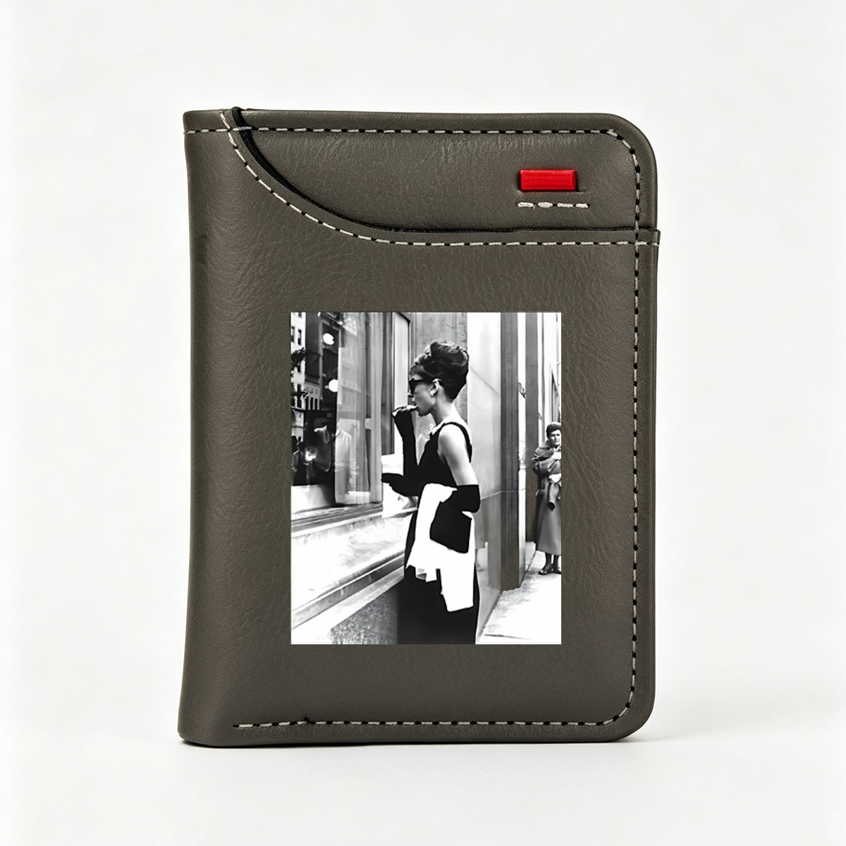 Audrey Hepburn in iconic black dress and sunglasses, standing by a window display, holding a white scarf and cigarette holder. - Vertical Style Wallet