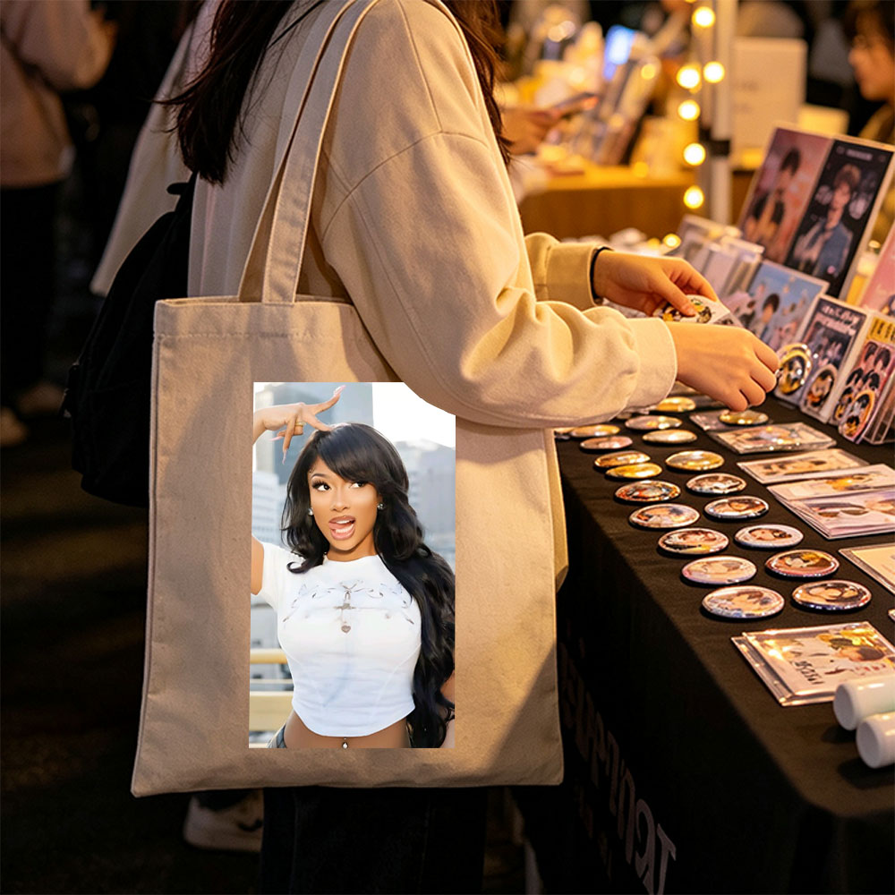 Megan Thee Stallion in a Bold Pose Wearing a White Crop Top with Cross Design and Long Black Hair Against a City Skyline Background - Canvas tote bags
