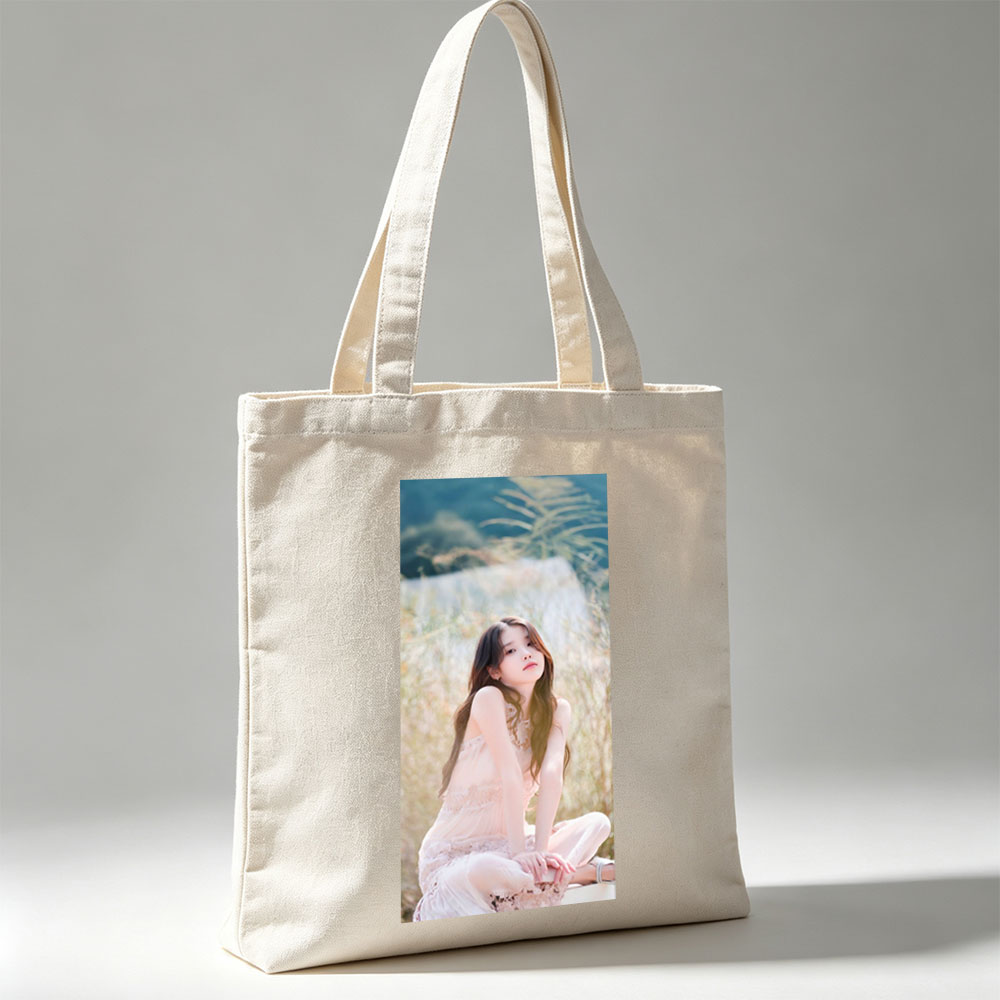 IU in a Serene Field Wearing a Delicate Pink Dress and Sitting Gracefully Amidst Tall Grass - Canvas tote bags